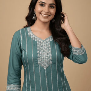 Woman wearing a green traditional outfit with white patterns on a beige background